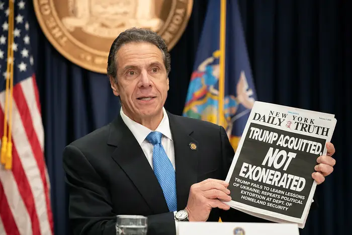 Governor Andrew Cuomo holds up a mock newspaper with the headline "Trump Acquitted, Not Exonerated," as he announced that New York will sue over the Trump administration's decision to cut off the state's access to Trusted Traveler programs.